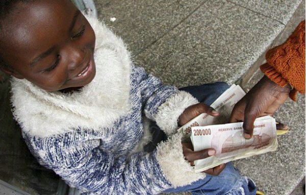 Декабрь 2007 г., мальчику-попрошайке дают мелочь — купюры по 200 000 зимбабвийских долларов.